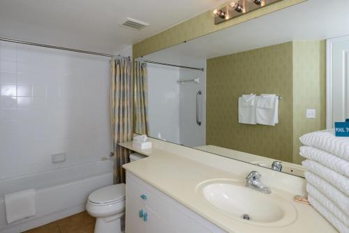 a bathroom with a sink and a toilet and a mirror at Discovery Beach Resort, a VRI resort in Cocoa Beach