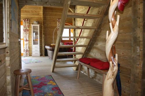 Cabaña de madera con escalera de caracol en una habitación en Villa Emilia - Gemütliches kinderfreundliches Blockhaus mit umzäuntem Garten en Sint Annaland