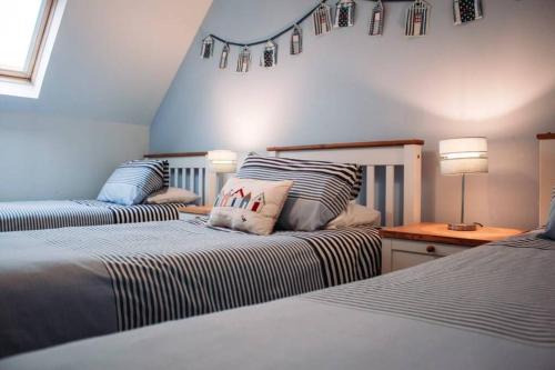 a bedroom with two beds and a table with a lamp at Craigewan Cottage Seatown Cullen in Cullen