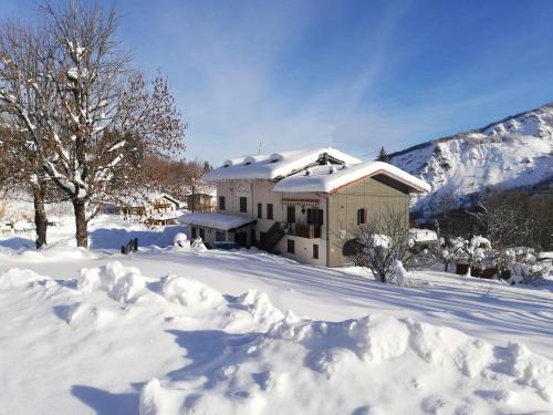 a house covered in snow with a pile of snow at La Buca delle Fate in Pievepelago