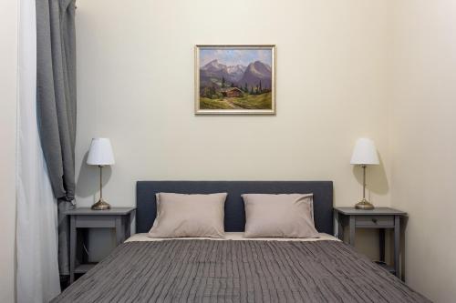 1 dormitorio con 1 cama con 2 mesas y una foto en la pared en Goldcentral Apartment, en Budapest