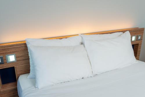 a bed with white pillows on top of it at Go2 Portishead Marina Hotel in Portishead
