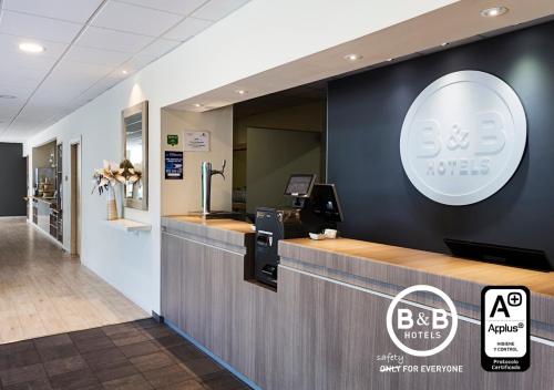 an office with a reception desk and a sign on the wall at B&B HOTEL Madrid Las Rozas in Las Rozas de Madrid