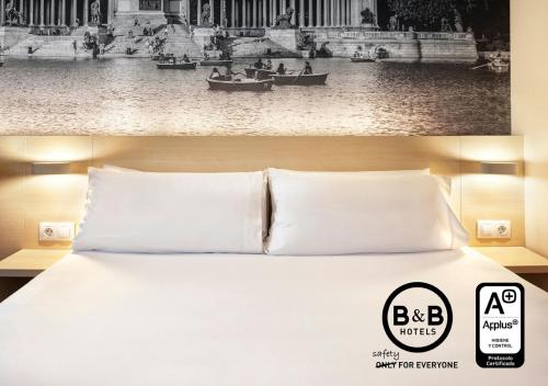 a bed in a hotel room with a black and white picture at B&B HOTEL Madrid Aeropuerto T1 T2 T3 in Madrid