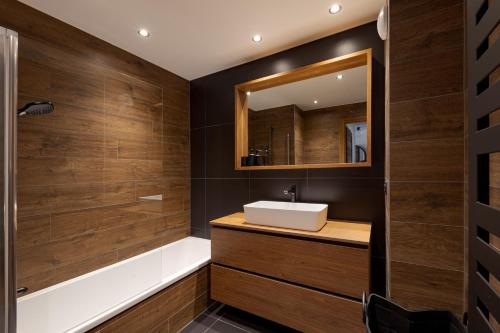 a bathroom with a sink and a tub and a mirror at Interlude Megeve in Megève