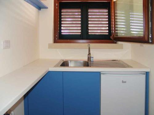 een keuken met blauwe kasten, een wastafel en een raam bij Residence la Vallona in Spongano