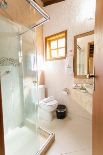 a bathroom with a toilet and a glass shower at Pousada Cantagalo in Itaipava