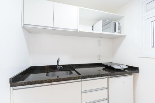 a white kitchen with a sink and a microwave at Apartamento impecável Fernando Machado 828 in Porto Alegre