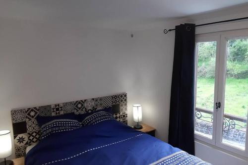 a bedroom with a bed with blue sheets and a window at La Petite Maison Dans la Vallée in Avallon