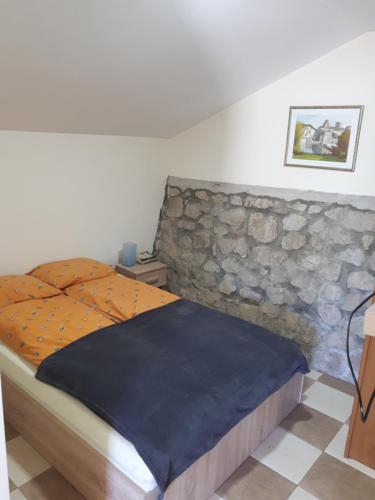 1 dormitorio con 1 cama con pared de piedra en Dedin raj en Golubac