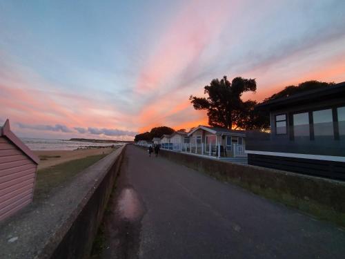 a person walking down a sidewalk next to the beach at Mudeford Beach Lodge in Mudeford
