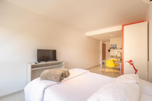 a white bedroom with a bed and a tv at Apartamento Rua Casemiro de Abreu, 199 in Porto Alegre