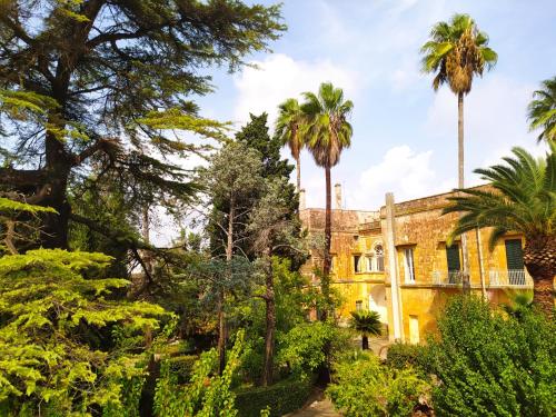 un antiguo edificio con palmeras y arbustos en Donna Bianca B&B, en Specchia