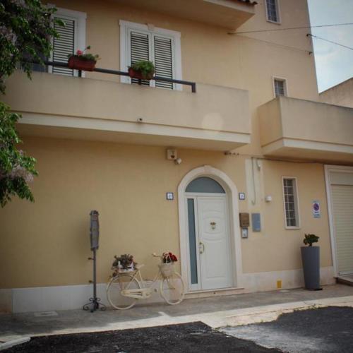 a white bike parked next to a building with a door at IL GIARDINO NASCOSTO in Portopalo