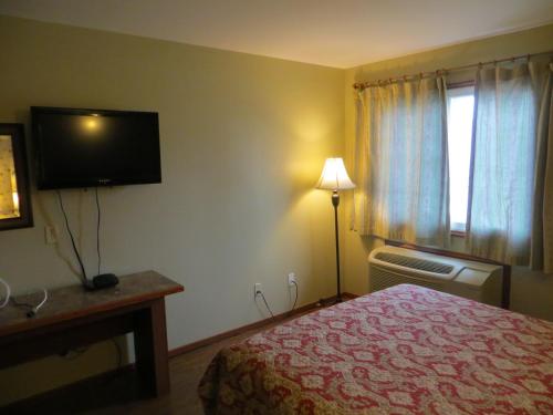 a hotel room with a bed and a flat screen tv at Queen Bee Hotel in Winnipeg