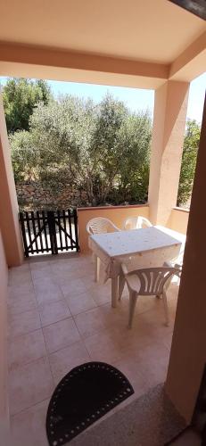 patio ze stołem i krzesłami na ganku w obiekcie Casa Vacanza Costa Rossa vista mare w mieście Trinità dʼAgultu