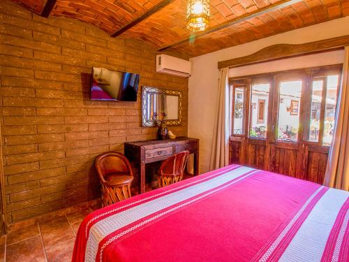 a bedroom with a bed and a desk and a television at Hotel Mi Pueblito Tapalpa in Tapalpa
