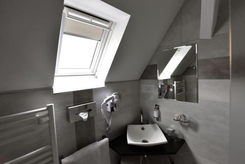 ein Bad mit einem Waschbecken und einem Fenster in der Unterkunft Hôtel de l'Ange in Niedermorschwihr