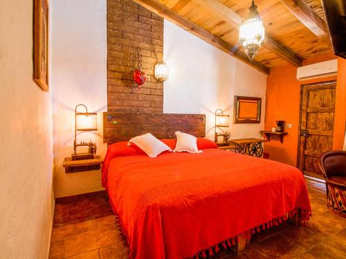 een slaapkamer met een rood bed met 2 kussens bij Hotel Mi Pueblito by Rotamundos in Tapalpa