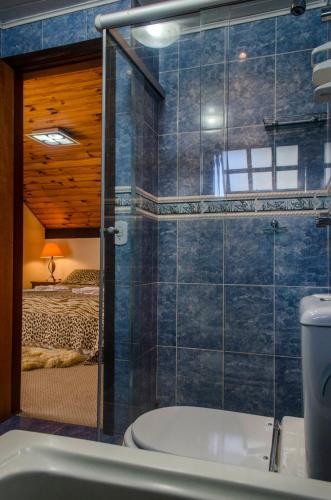 a bathroom with a tub and a toilet and a bedroom at Pousada Heron in Campos do Jordão