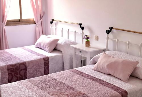 a bedroom with two beds and a table and a window at Apartamento El Jazmín in Grazalema