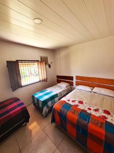 1 dormitorio con 2 camas y ventana en Casa com Wi-Fi e lazer em Porto de Pedras - AL, en Tatuamunha