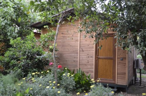 a wooden shed with a wooden door in a garden at mercan pension in Olympos