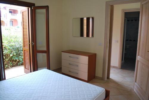 1 dormitorio con cama, tocador y espejo en Appartamenti Golfo Aranci, en Golfo Aranci