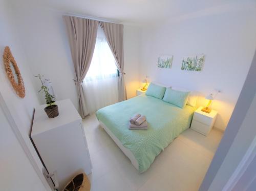 a small white bedroom with a bed and a window at Casa Contento by Sea You There Fuerteventura in Corralejo