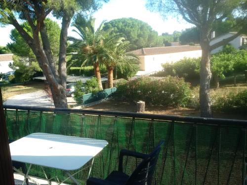 a balcony with a table and chairs and palm trees at Les Lucioles in Cavalaire-sur-Mer