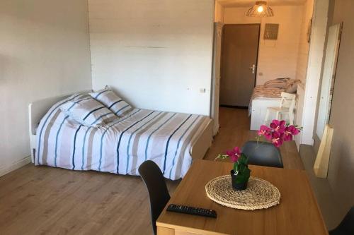 una habitación con una cama y una mesa con flores. en Magnifique Studio Cassis, en Cassis