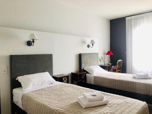 a hotel room with two beds with towels on them at Hôtel Le Cro-Magnon in Les Eyzies-de-Tayac