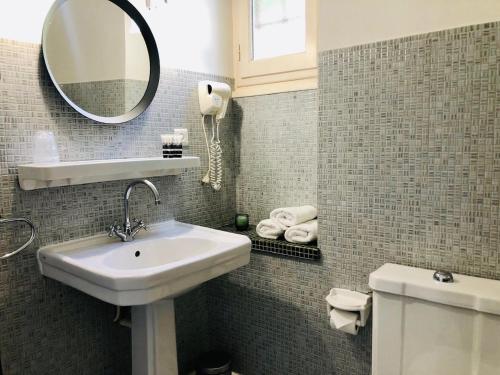 a bathroom with a sink and a mirror and a toilet at Hôtel Le Cro-Magnon in Les Eyzies-de-Tayac