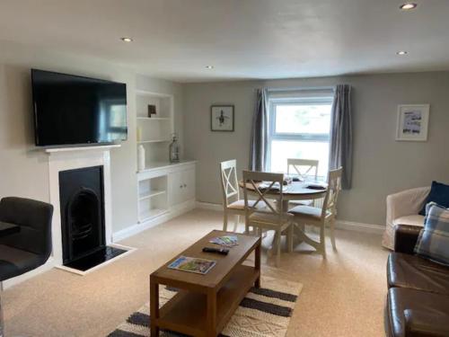 a living room with a couch and a table and a fireplace at St Margarets Penthouse Apartment in Ryde