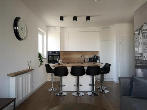 a kitchen with black bar stools and a counter at Apartamenty 48 Letnica in Gdańsk