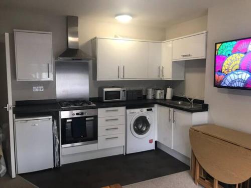 a kitchen with white cabinets and a washing machine at St Margaret's Ground Floor and Lower Deck Apartment in Ryde