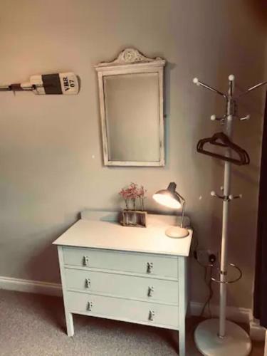a white dresser with a lamp and a mirror at St Margarets Modern Georgian 2 bedroom apartment in Ryde