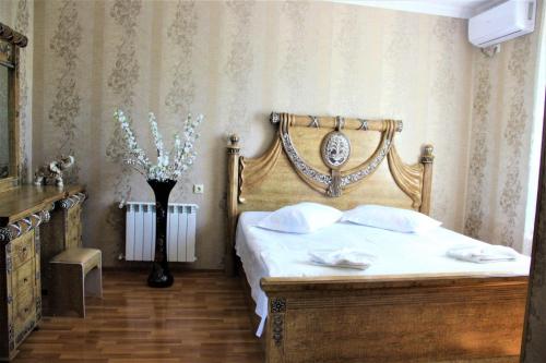 een slaapkamer met een bed met een houten hoofdeinde bij Hotel Oniks in Koetaisi