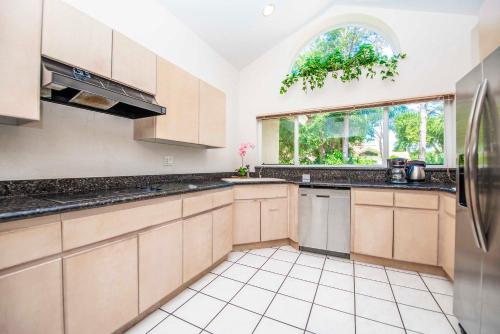 a kitchen with wooden cabinets and a large window at SWISS 41 - Golf Course in Clermont