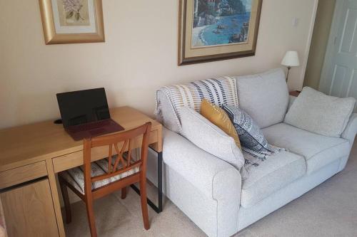 a living room with a couch and a desk with a laptop at The Burrow, a Spacious Bungalow in Heart of NI in Templepatrick
