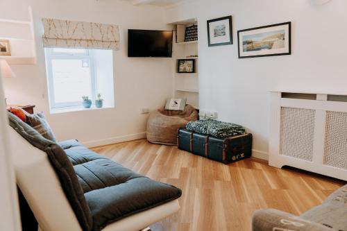 a living room with a couch and a television at Hamilton Lodge - Cottage sleeps 8 in Fishguard