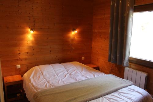a bedroom with a bed in a wooden wall at Chalet Les Bouleaux, la montagne des lamas in La Bresse
