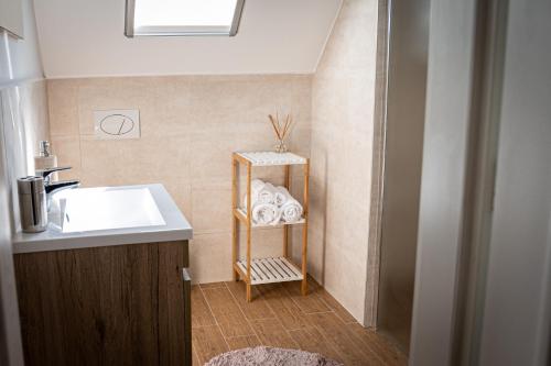 a bathroom with a sink and a shelf with towels at Szigligeti Mandula Kert Vendégház in Szigliget