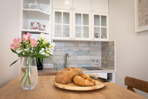 a table with a plate of bread and a vase of flowers at Szigligeti Mandula Kert Vendégház in Szigliget