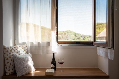 a glass of wine sitting on a table next to a window at Szigligeti Mandula Kert Vendégház in Szigliget