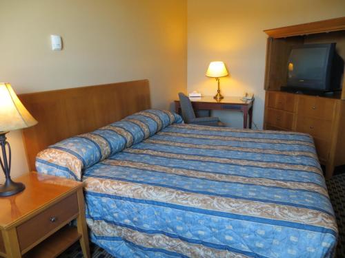 a hotel room with a bed and a television at Athabasca Valley Inn & Suites in Hinton