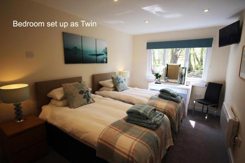 a bedroom with two beds and a desk and a window at The Cabin at Easter Arr in Auldearn