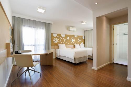 a hotel room with a bed and a desk and a bedroom at Mercure Sao Paulo Alamedas in Sao Paulo