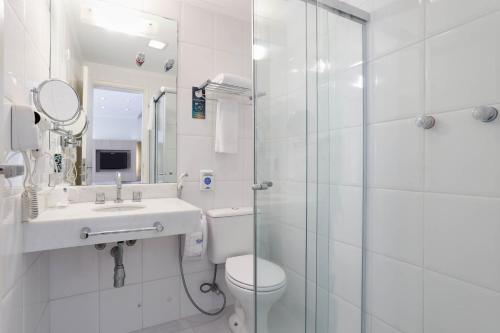 a bathroom with a toilet and a sink and a shower at Mercure Sao Paulo Alamedas in Sao Paulo
