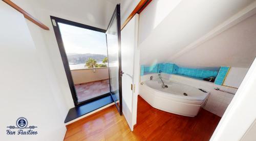 an attic bathroom with a tub and a window at WELCOME RIVIERA - ATTICO SAN FAUSTINO 165 mq più 110 mq di terrazza- IN VILLA 700 ,VISTA MARE STREPITOSA-100 m dalla spiaggia-PARKING ESCLUSIVO in Rapallo